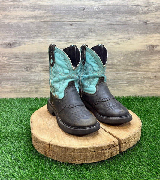 Pair of black cowboy boots with turquoise design on a wooden platform